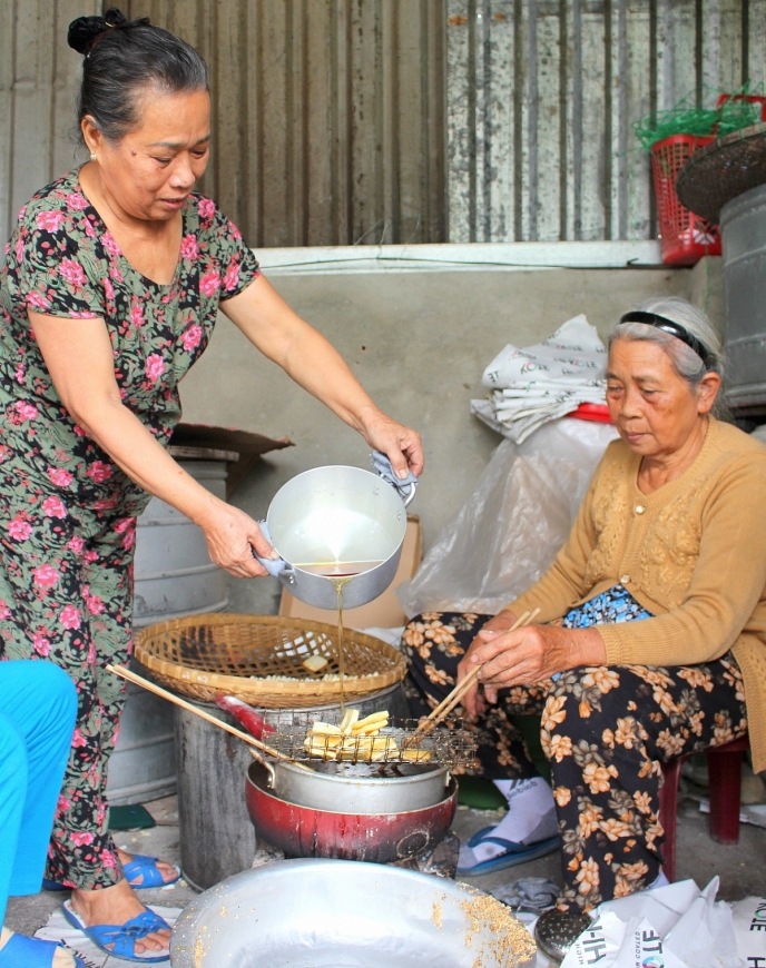 Bà Nguyễn Thị May (bên trái) và bà Nguyễn Thị Nghĩ đang tiếp đường thắng. Những phụ nữ cao tuổi “giữ hồn” bánh khô mè