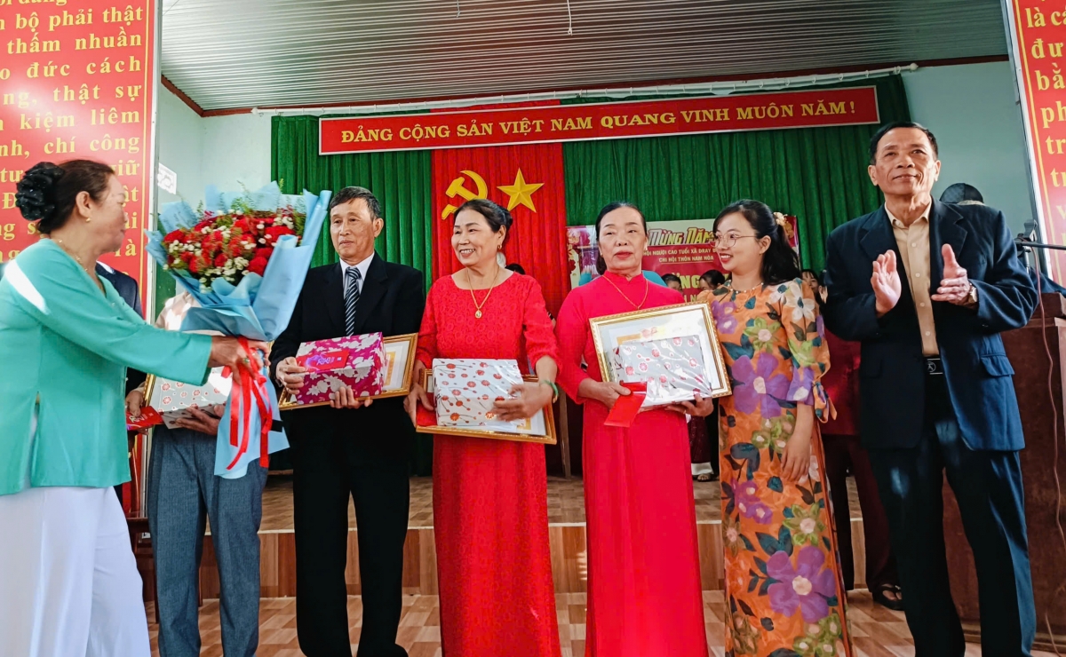 ông Nguyễn Hồng Khanh, Chủ tịch Hội NCT xã trao tặng giấy mừng thọ và quà của UBND xã Dray Bhăng cho NCT thôn Nam Hoà.