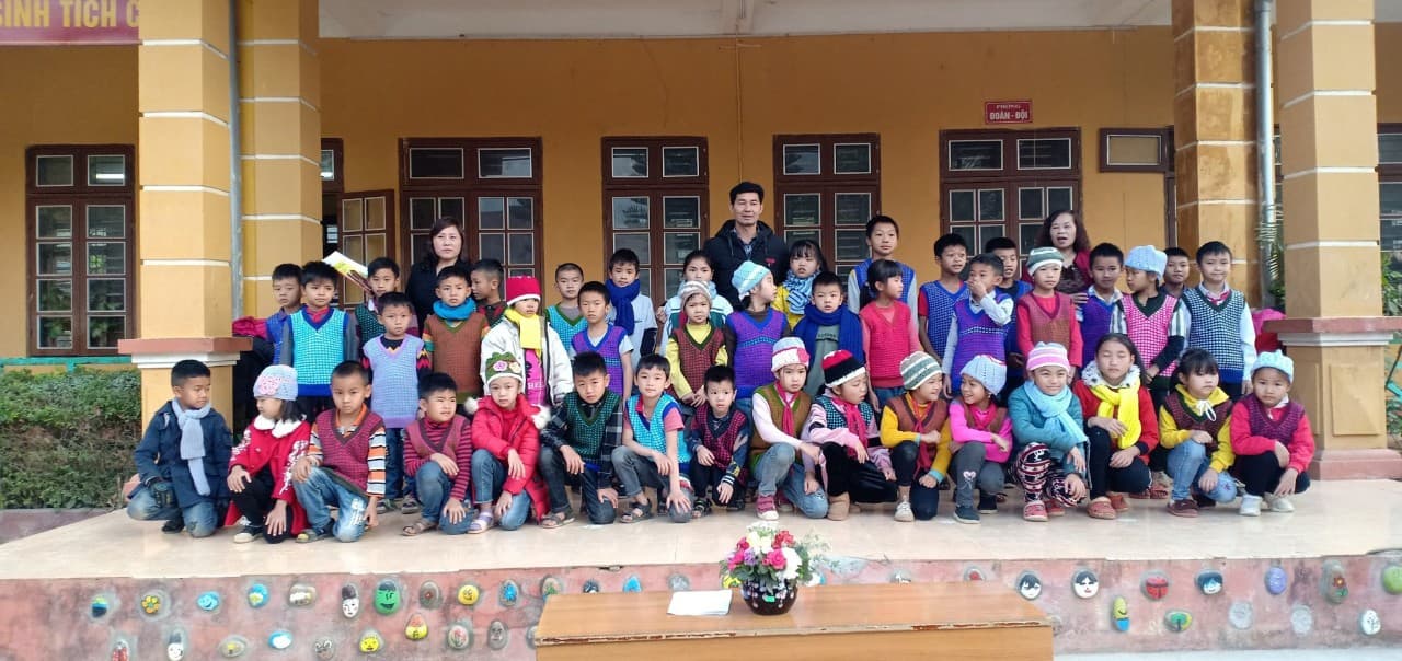 C&aacute;c ch&aacute;u thiếu nhi trường Tiểu học Đ&ocirc;ng Sang mặc &aacute;o, đội mũ, qu&agrave;ng khăn do cụ Nguyễn Thị &Acirc;n trao tặng